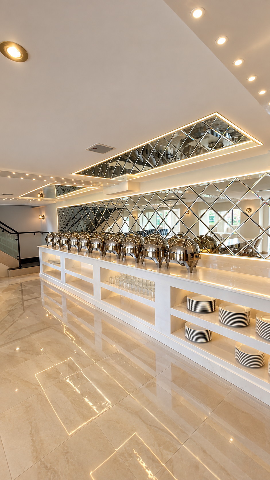 The servery at Kashmiri Karahi: a fitted white counter with chafing dishes, a mirrored diamond splashback and open shelving beneath.