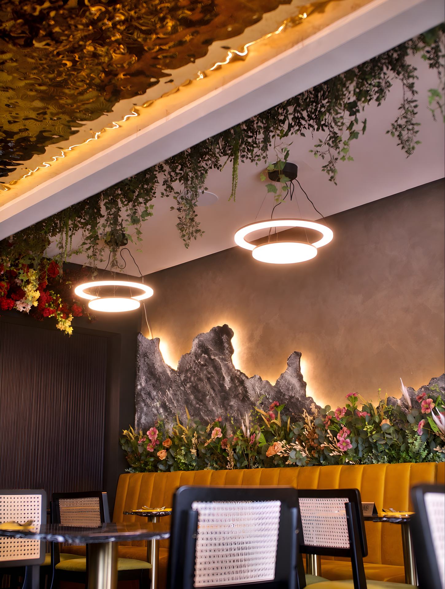 Ring lights, the backlit rock-relief wall, hanging foliage and the mustard banquette.